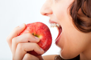 Healthy nutrition and healthy teeth or diet, young woman bites in a apple